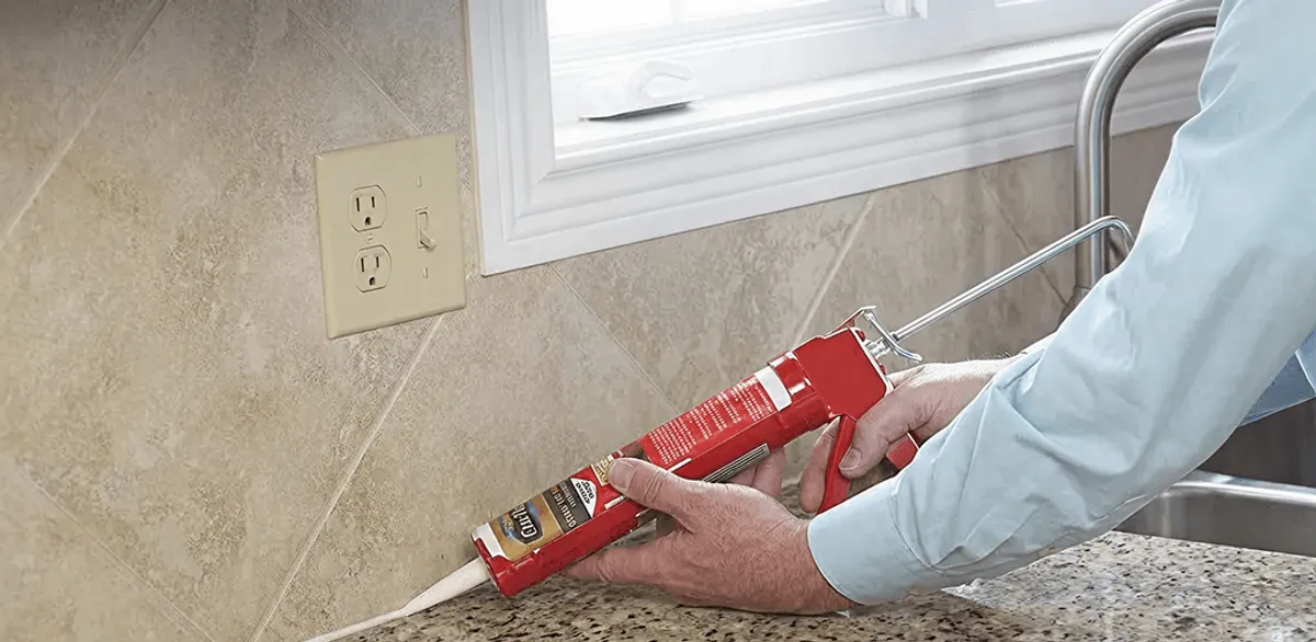 Handyman applying caulk along a kitchen backsplash and countertop seam in Jersey City, NJ